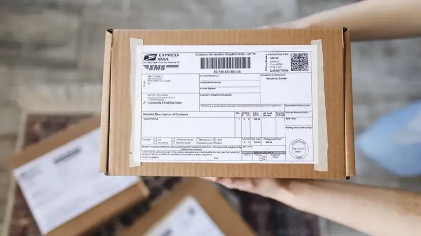 EMS 국제소포 상자에 붙은 통관 신고서(Customs Declaration)를 들고 있는 손